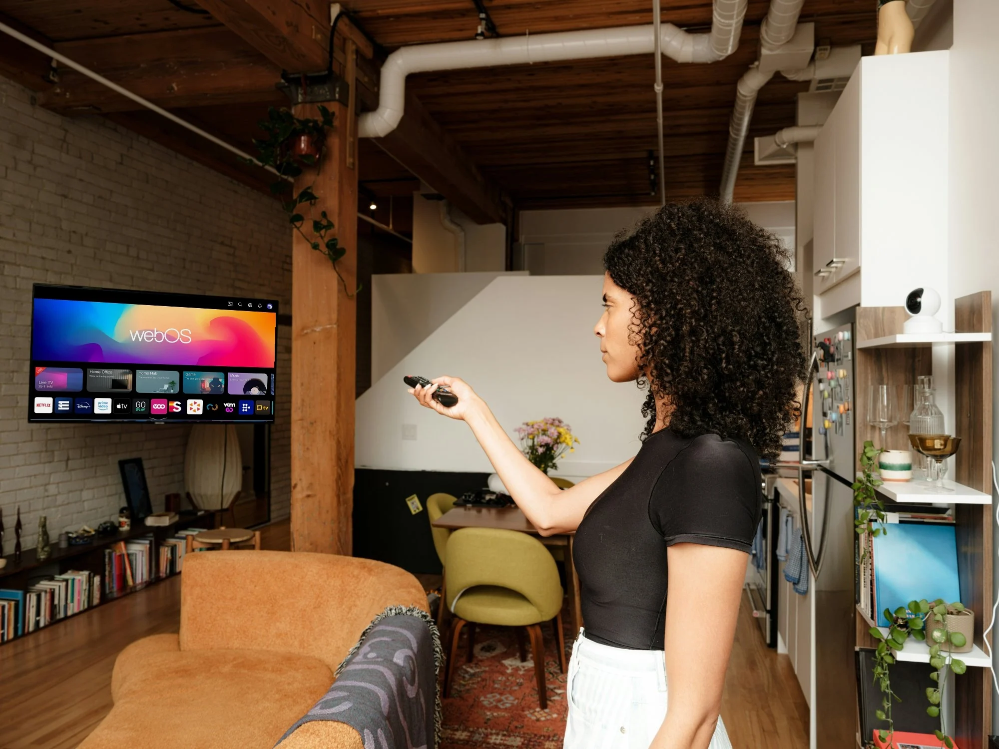 Woman using the remote with a Playstar webOS Smart TV in a modern living room